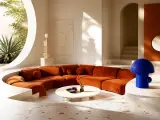 Sunlit sculptural living room with an orange curved sofa and cobalt-blue lamp