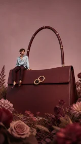 Fashion poster with a giant burgundy leather bag and a miniature male model